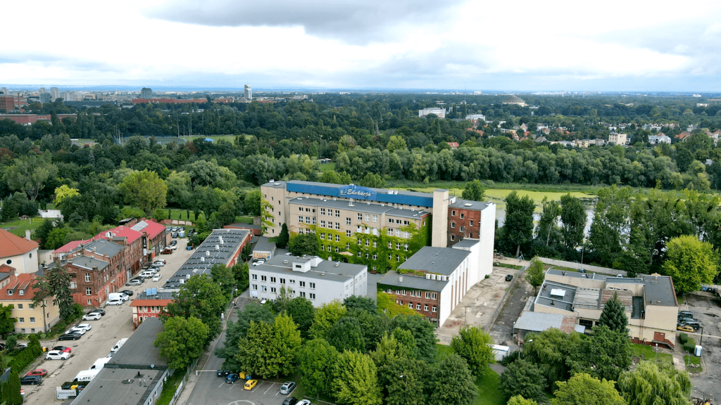 Nowoczesne zdjęcie siedziby Synergy Trainings przy ul. Krakowskiej 56-62 we Wrocławiu, z widokiem na pobliskie budynki i rzekę.